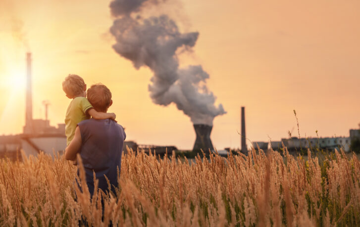 Otec a syn se dívají z přírody na kouřící komín